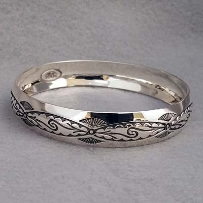 Half-inch wide sterling silver bangle with hand stamped Pueblo Scroll design.  Native American made.